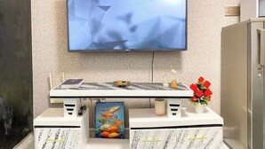 Een moderne keuken met een flatscreen televisie boven een wit aanrecht.