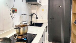 Een keuken met een fornuis, een gootsteen, een blender en een zwarte koelkast.