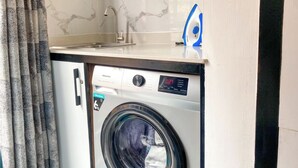 Een compacte wasmachine en droger combinatie met een digitaal display, een wasbak en een blauw-wit gestreken ijzer.