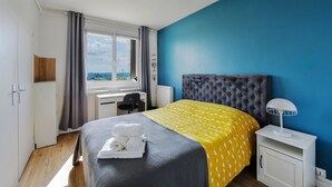 A bedroom with a bed, a desk, a chair, a lamp, and a view of the outdoors. - T4, Crossing, 3bed, quiet, Metro D'parking 7 /7.  Secure residence. (Vénissieux)