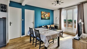 A dining area with a table set for four, a ceiling fan, and a large window with curtains. - T4, Crossing, 3bed, quiet, Metro D'parking 7 /7.  Secure residence. (Vénissieux)