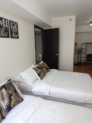 A bedroom with a bed, two pillows, a door, and a fan. - Spacious Suite in Pasig Cityurban Metro Escape (Pasig)