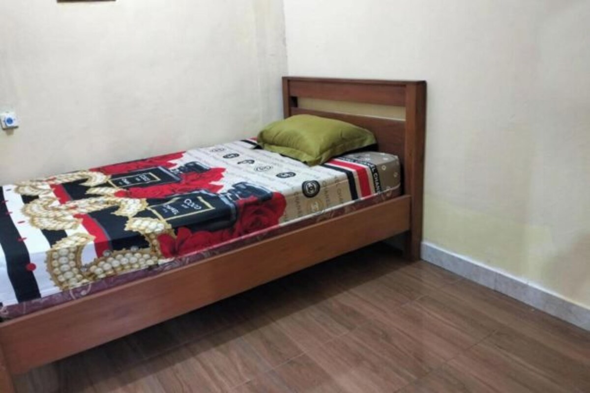 Uma cama de solteiro com estrutura de madeira e colcha estampada.