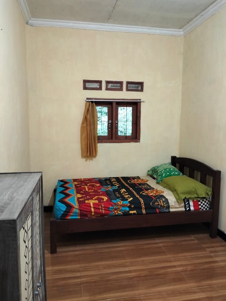 Un dormitorio con una cama de madera, un ventanal con cortinas y una repisa sobre la ventana.