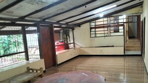 A spacious room with a large wooden table, a bench, and a view of a red car outside. - Villa Ndelik Ijen (Banyuwangi)