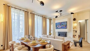 Un soggiorno moderno con zona pranzo, divano, televisione a schermo piatto e camino.