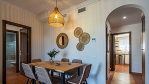 A dining area with a wooden table and wicker chairs, a hanging light fixture, and decorative wall mirrors. - Los Gavilanes - Isla Canela Beach ICLHG62SP (Isla Canela)