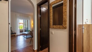 A hallway with a dark wooden door, a woven mirror, and a view into a dining area with a table and chairs. - Los Gavilanes - Isla Canela Beach ICLHG62SP (Isla Canela)