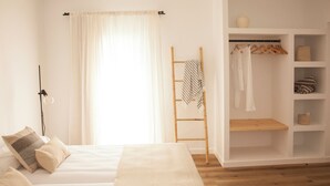 Un dormitorio con cama, armario y ventana con cortinas.