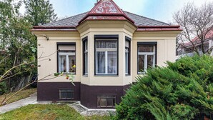 A two-story house with a bay window, a red roof, and a small front porch.