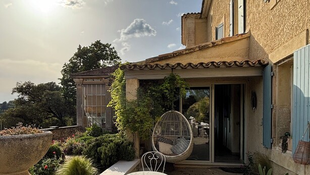 An outdoor patio with a table and chairs, a hanging chair, and potted plants. - Villa Bam Bam (Apt)