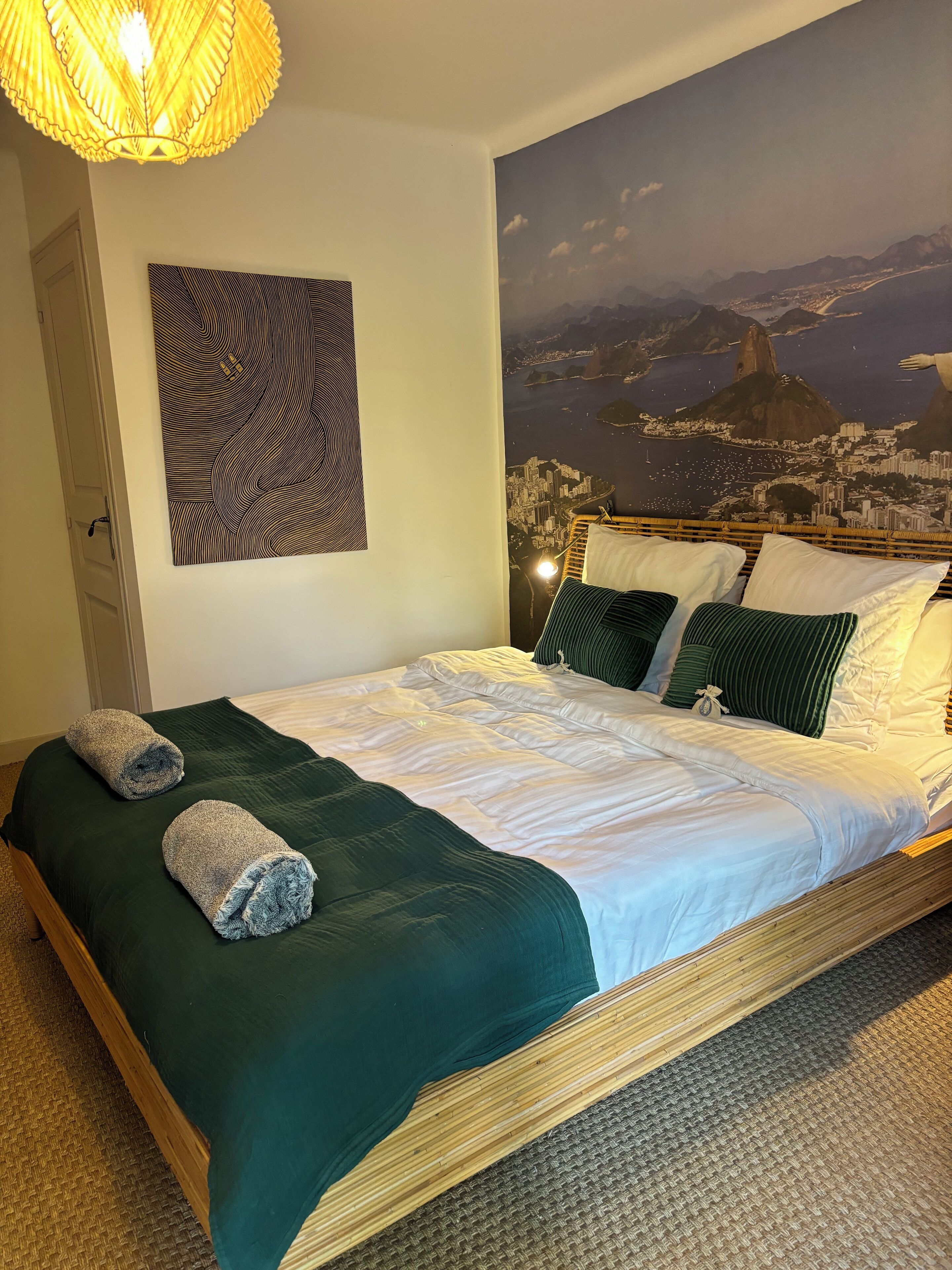 Una camera da letto con un letto, cuscini, una coperta, un quadro appeso al muro e una porta.