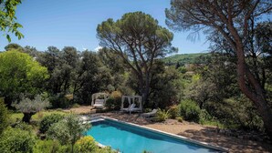 A swimming pool surrounded by lush greenery and trees, with a gazebo and lounge chairs in the background. - Villa Bam Bam (Apt)