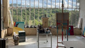 A spacious room with large windows, a chandelier, and various art supplies and furniture. - Villa Bam Bam (Apt)