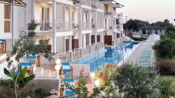 Un hotel a più piani con balconi, piscina e posti a sedere all'aperto.