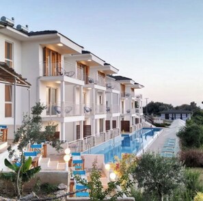 A multi-story hotel with balconies, a swimming pool, and outdoor seating. - Bubo Faralya Suite Hotel (Fethiye)