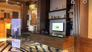 A reception area with a modern design, featuring a reception desk, a digital screen, and a large poster. - Experience comfort in this affordable studio, complete with all you need. (Cebu City)