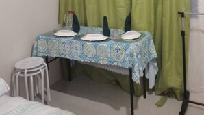 A small dining area with a table set for two, a chair, a small stool, and a curtain. - Experience comfort in this affordable studio, complete with all you need. (Cebu City)