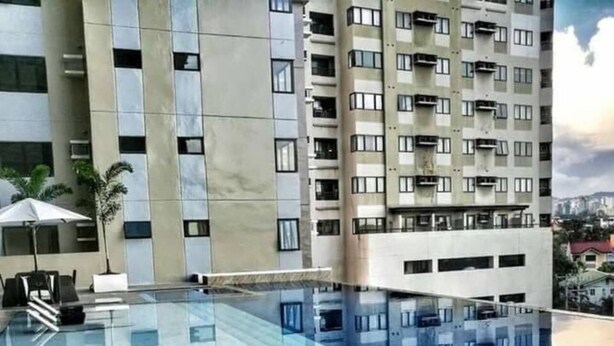 A modern hotel with a rooftop infinity pool, a terrace with outdoor seating, and a view of surrounding buildings. - Experience comfort in this affordable studio, complete with all you need. (Cebu City)