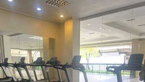 A gym with multiple treadmills, a mirrored wall, and a view of the outside. - Experience comfort in this affordable studio, complete with all you need. (Cebu City)