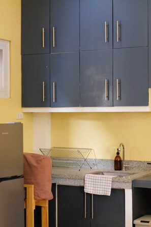 A kitchen with dark cabinets, a countertop, a sink, and a small refrigerator. - 2BR laid back apartment, near beach (San Fernando City)