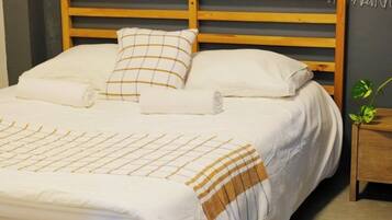 Uma cama bem arrumada com cabeceira de madeira, um travesseiro e um cobertor.