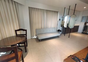 A modern living room with a dining table, a sofa, and a kitchen area with a refrigerator. - Suite Deluxe Beachfront near Mactan Cebu Airport,in Tambuli Seaside Condominiums (Lapu-Lapu)