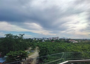 A view of a residential area with a dirt path, greenery, and buildings in the distance under a cloudy sky. - Suite Deluxe Beachfront near Mactan Cebu Airport,in Tambuli Seaside Condominiums (Lapu-Lapu)