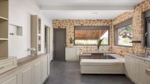 Una cocina moderna con una pared de acento de piedra, armarios empotrados y un amplio ventanal con vistas al exterior.