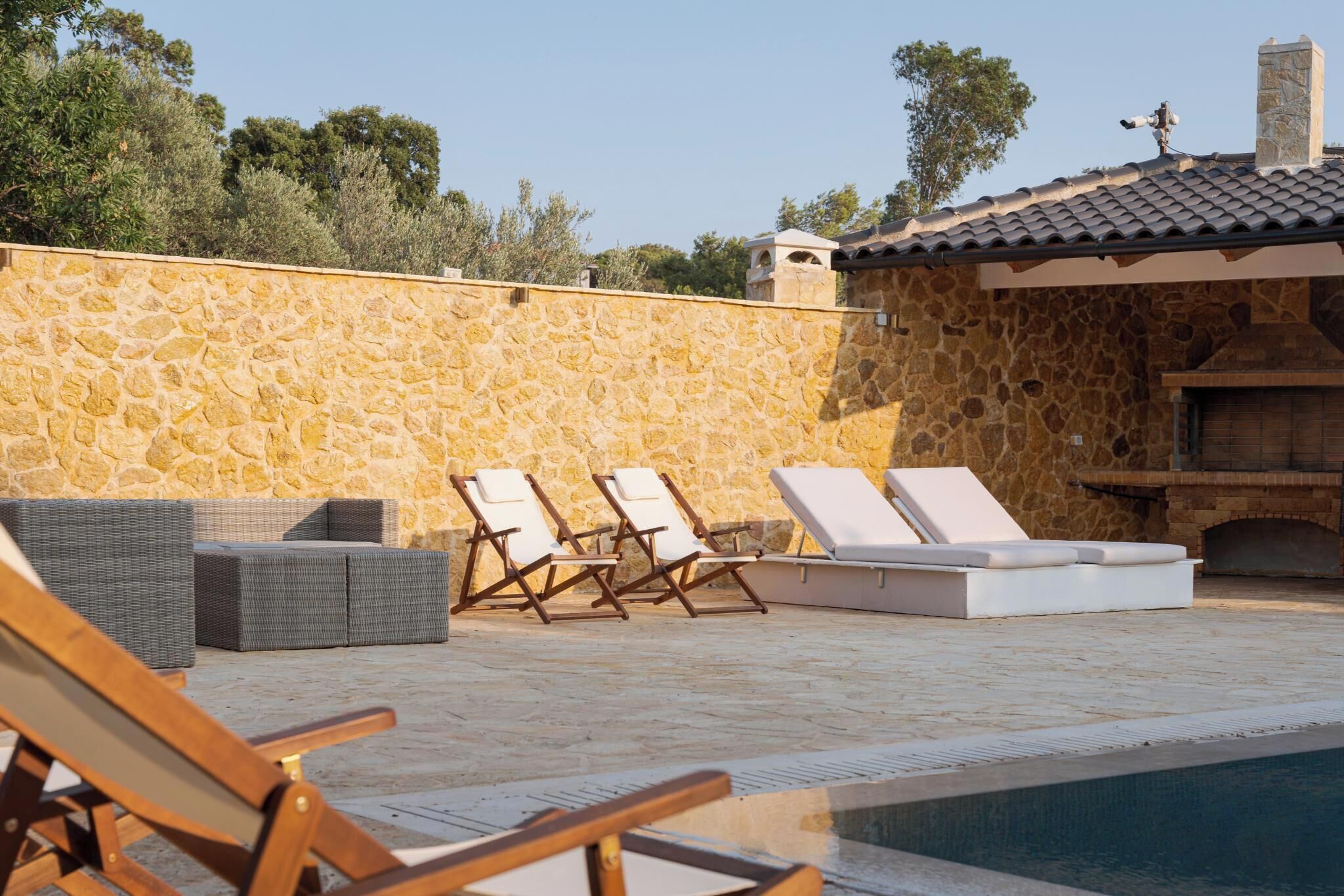 Un muro in pietra, posti a sedere all'aperto e una piscina.