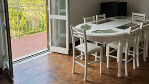 Ein Essbereich mit einer Glastür, die auf einen Balkon mit Blick auf grüne Hügel führt.