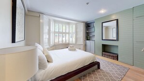 A bedroom with a bed, a window, a mirror, and built-in shelving.