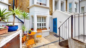 A small courtyard with a white bench, a table, and potted plants.