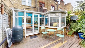 A corner room with a bay window, a large water tank, and a patio with a table and chairs.