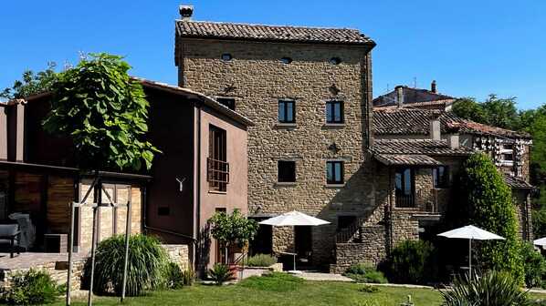 A stone building with a courtyard, outdoor seating, and a staircase leading to an upper level.