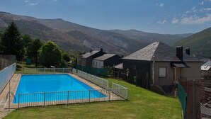 Una piscina con valla blanca, rodeada de casas y montañas al fondo.