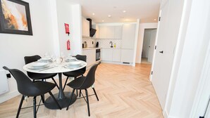 A modern kitchen with white cabinets, a black range hood, and a built-in oven. - Central Manchester 2BR Apt in Lomax Street (Manchester)
