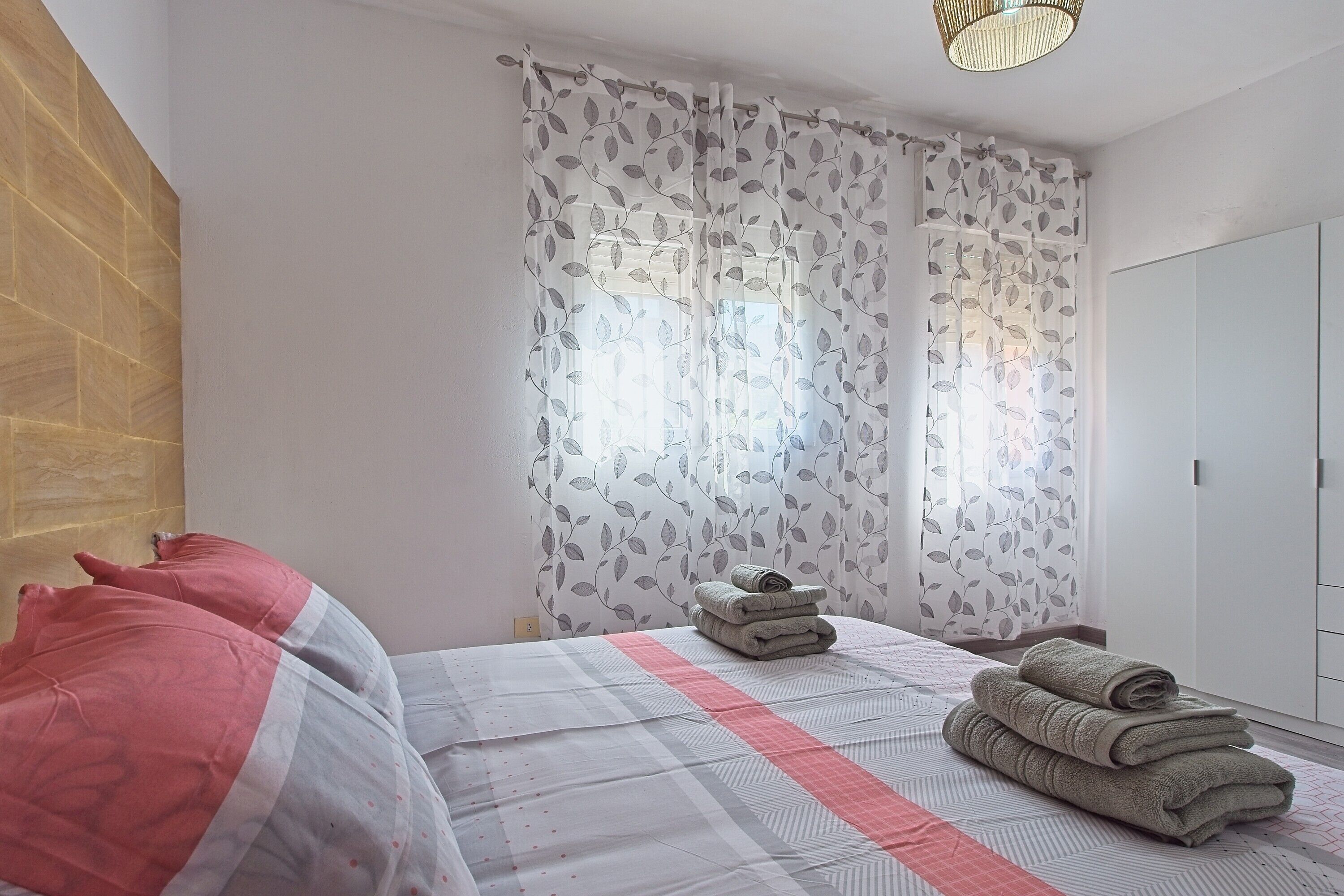 Une chambre à coucher avec un lit, des oreillers, une serviette enroulée et une armoire.