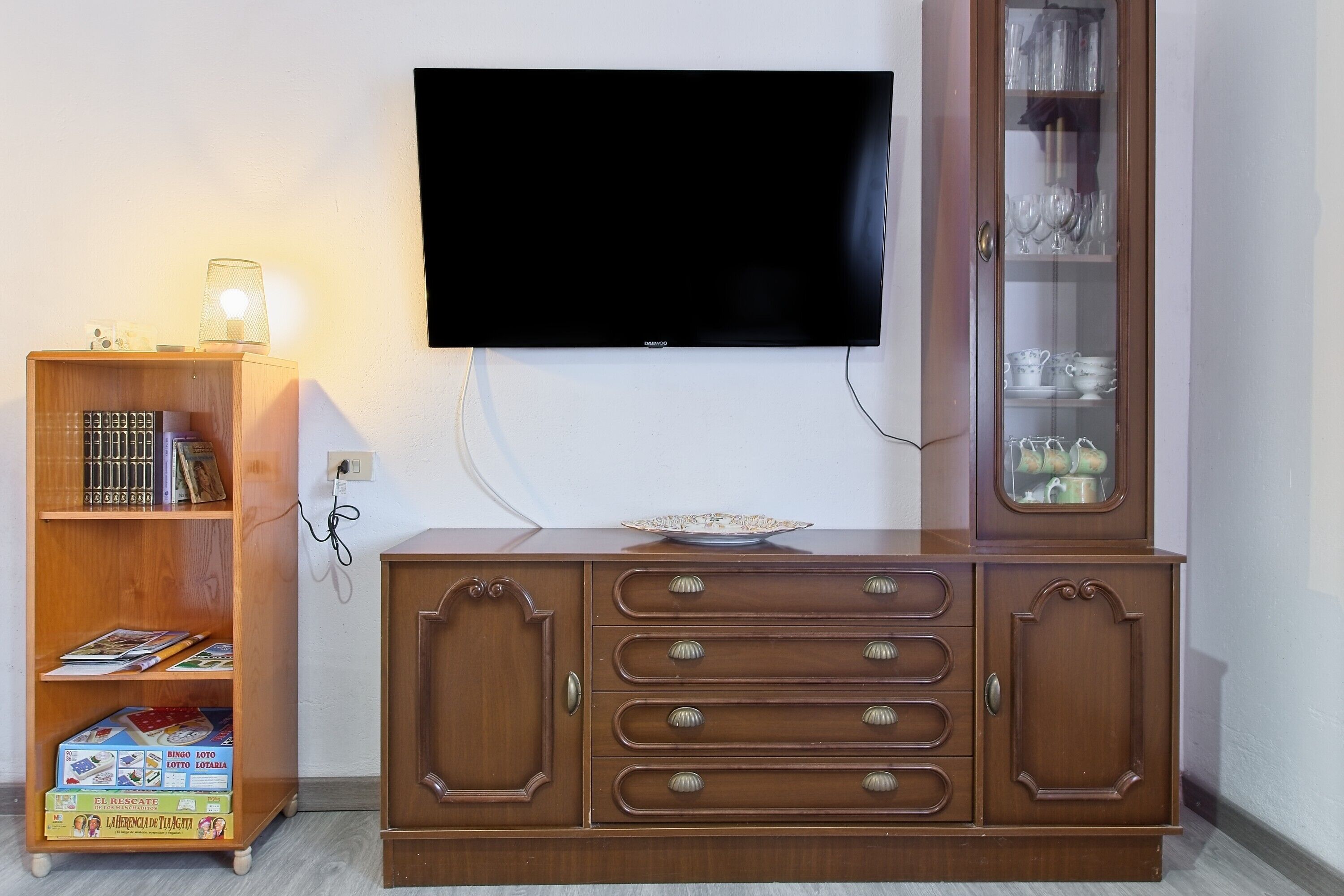 Een houten kast met lades en een televisie aan de muur.
