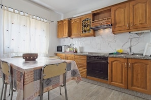 A kitchen with wooden cabinets, a stove, a microwave, and a sink.