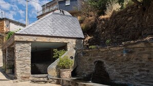 A stone structure with a tiled roof, a small water feature, and a stone wall.