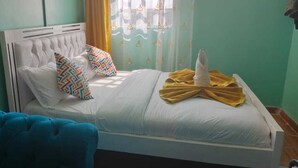A bed with a white headboard, multiple pillows, and a yellow towel on the bed.