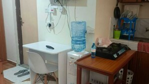 A small kitchenette with a white countertop, a water dispenser, a small table, and a chair.