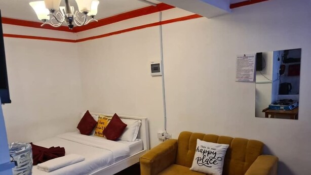 A room with a bed, a sofa, a coffee table, and a small table with a water bottle.