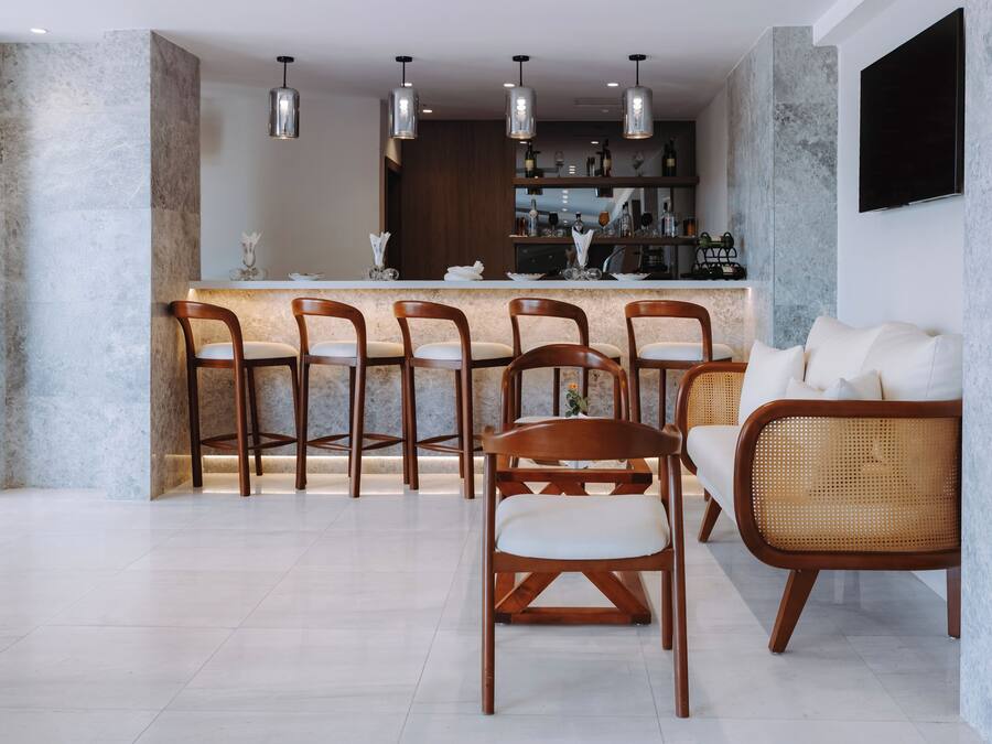 A modern kitchen with a bar area, wooden chairs, and a white sofa.