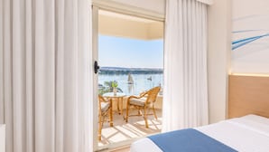 Habitación de hotel con balcón, una cama y vistas al agua.