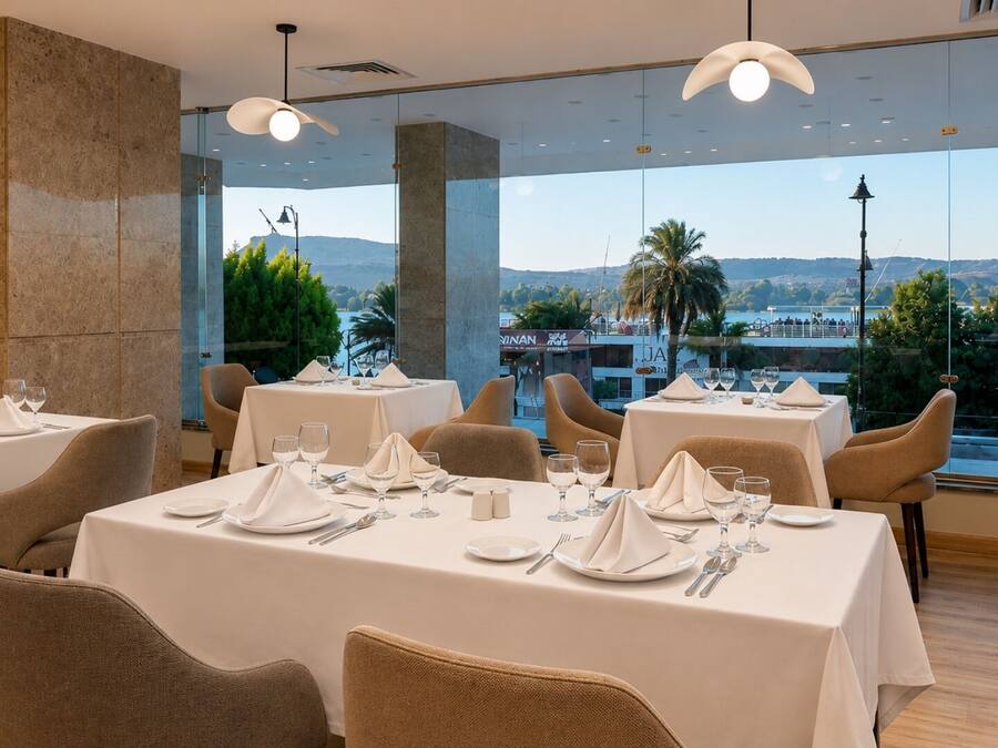 A restaurant with tables set for dining, large windows offering a view of the cityscape, and modern interior design.