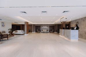 A hotel lobby with a reception desk, sofas, and a large wall with the hotel's name. - Obelisk Nile Towers (Aswan)