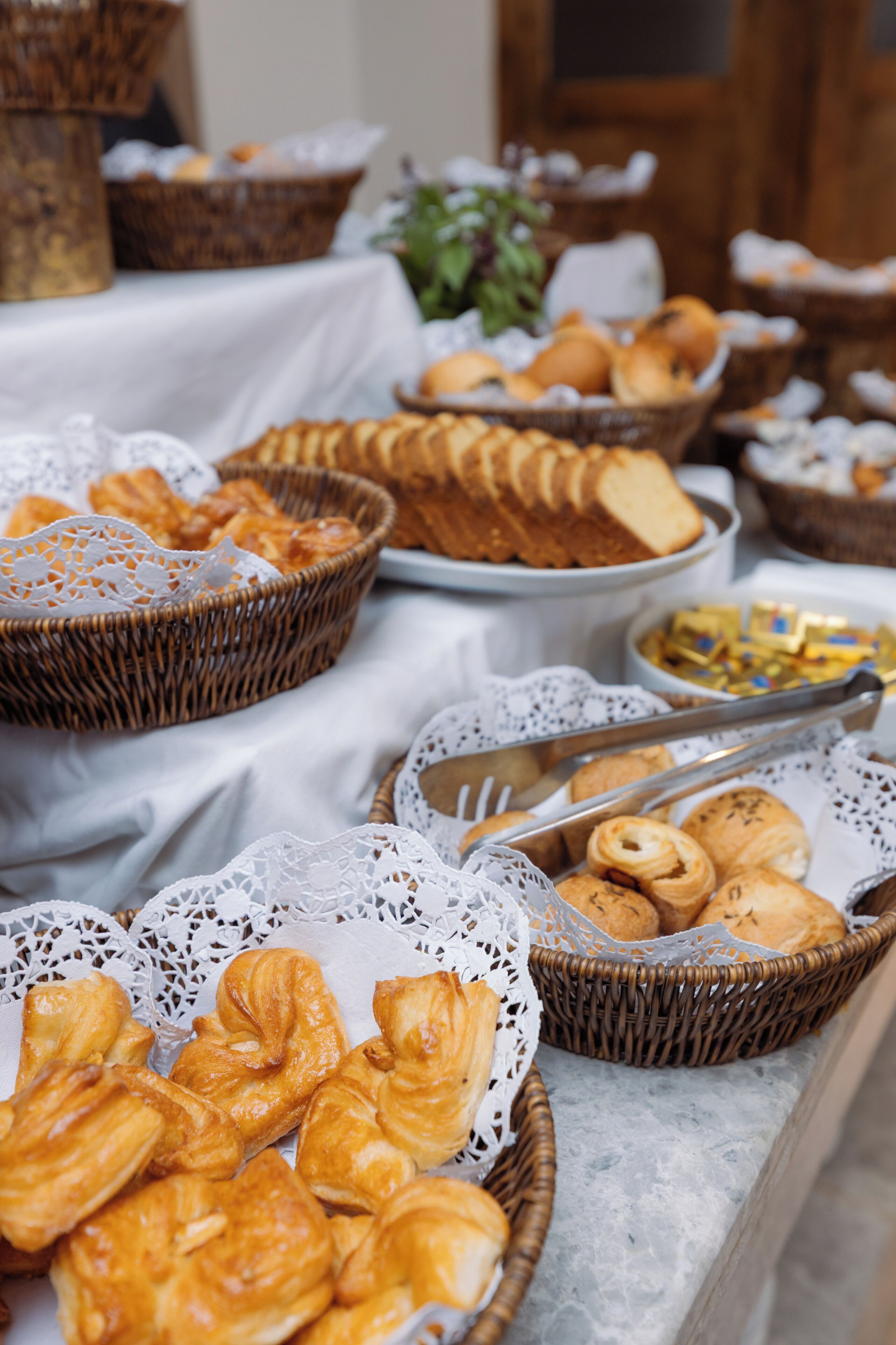 Uma mesa de buffet com diversos produtos de panificação e doces.