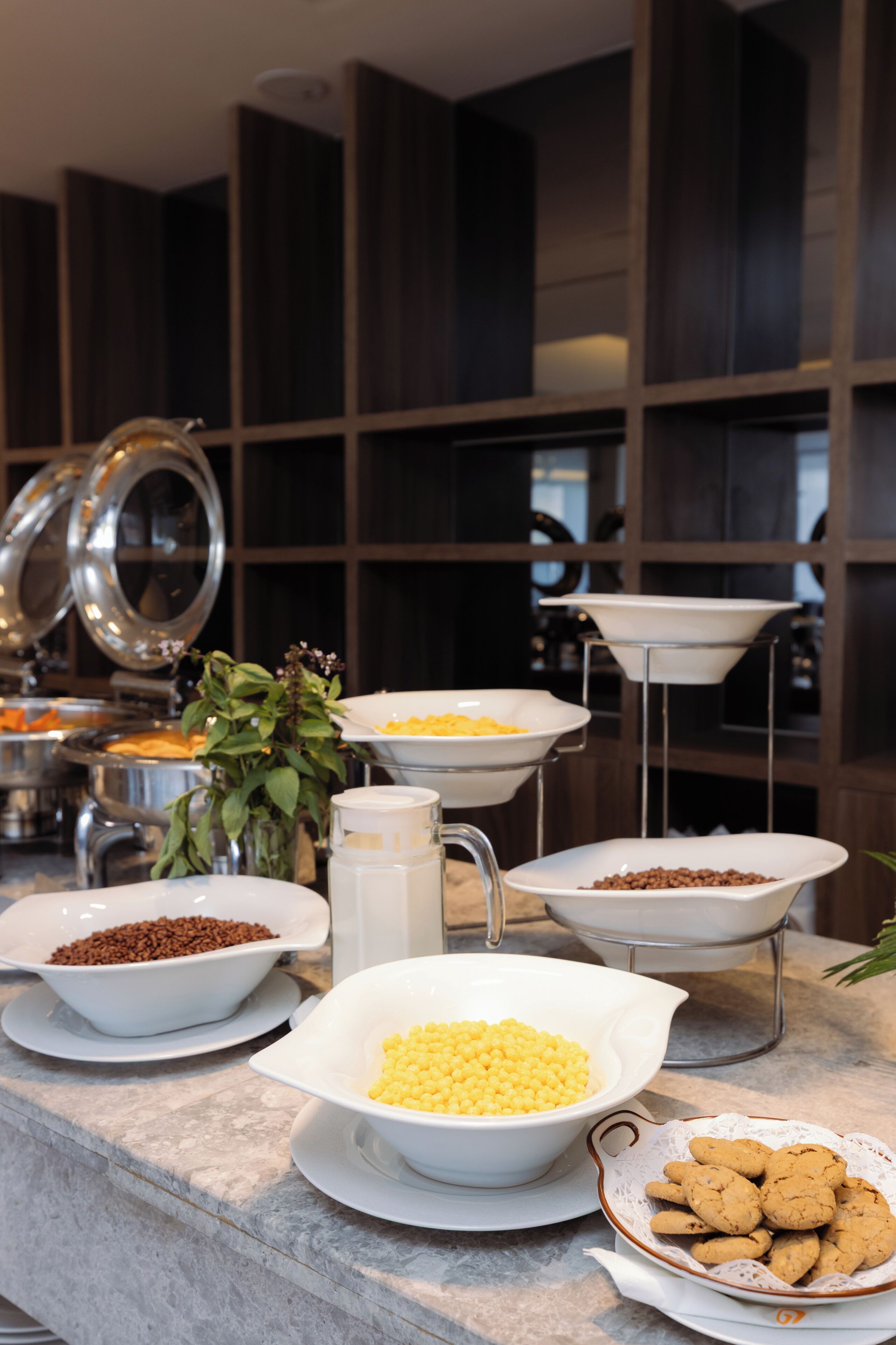 A buffet setup with various food items and a decorative plant.